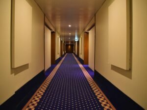 Blauer und roter Teppich verlaufen nebeneinander durch einen hellen Flur in einem modernen Gebäude