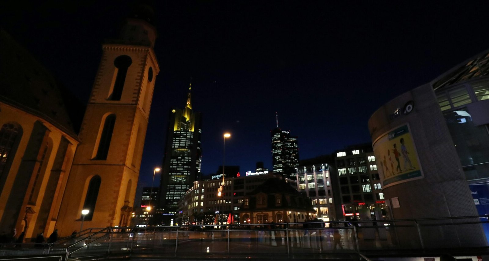 Städtischer Ausblick bei Nacht, aufgenommen von einer Rolltreppe mit Blick auf beleuchtete Gebäude