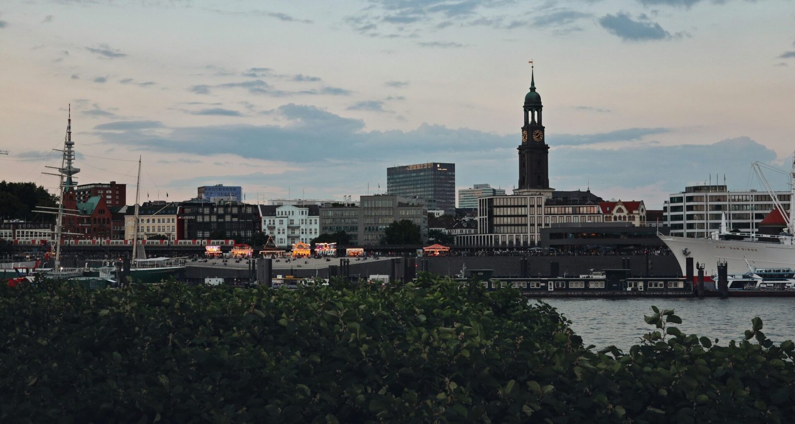 Blick über das Wasser auf eine Stadt mit Skyline und Ufer, fotografiert aus der Ferne bei Tageslicht