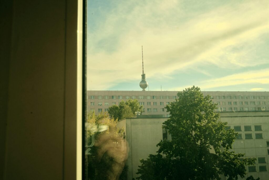 Städtische Aussicht durch ein Fenster auf einen Fernsehturm im Hintergrund eines Gebäudes