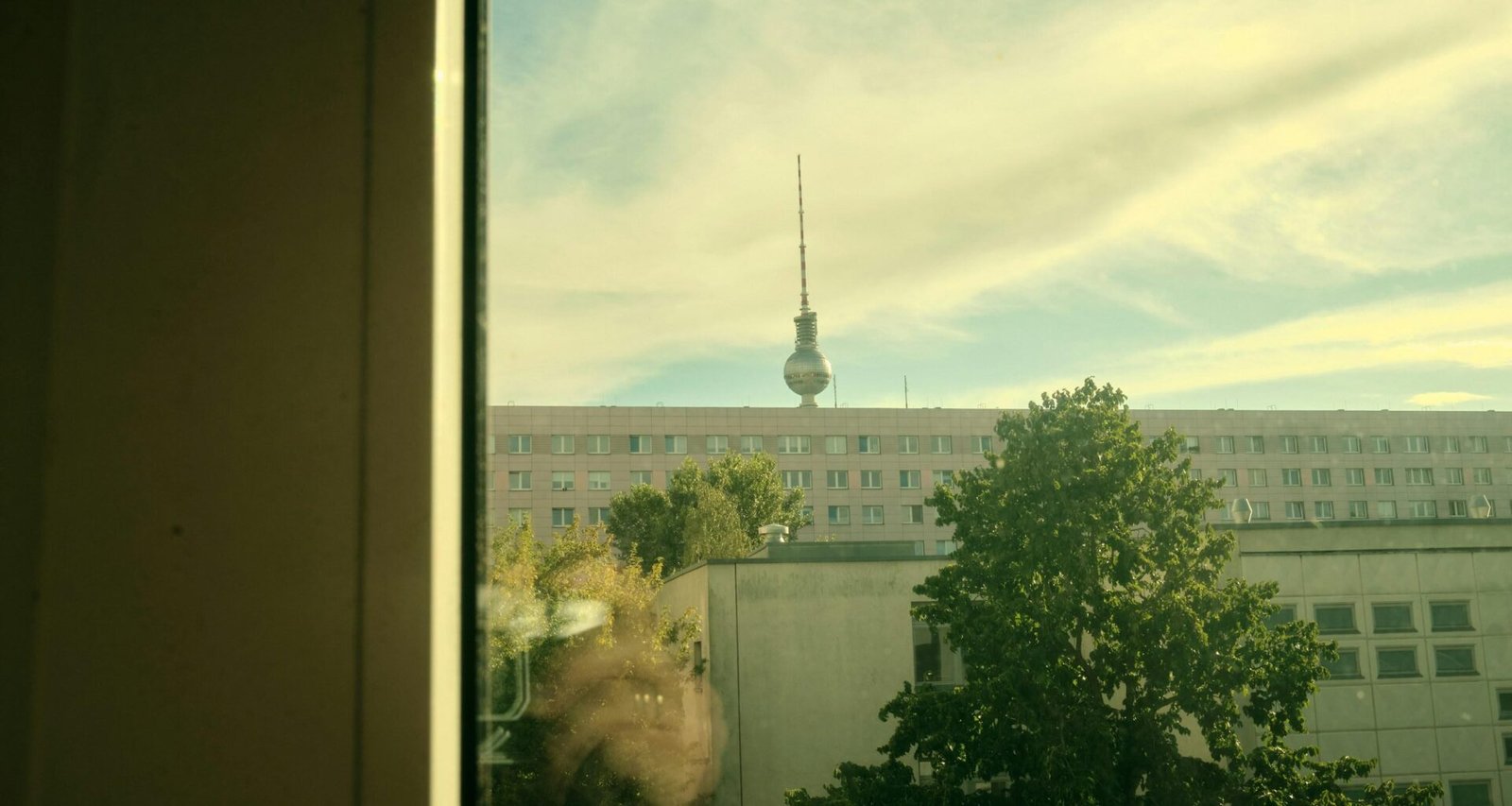 Städtische Aussicht durch ein Fenster auf einen Fernsehturm im Hintergrund eines Gebäudes