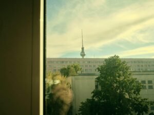 Städtische Aussicht durch ein Fenster auf einen Fernsehturm im Hintergrund eines Gebäudes