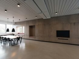 Brauner Holztisch mit Stühlen vor einem großen Fenster in einem modernen Raum mit viel Tageslicht