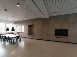 Brauner Holztisch mit Stühlen vor einem großen Fenster in einem modernen Raum mit viel Tageslicht