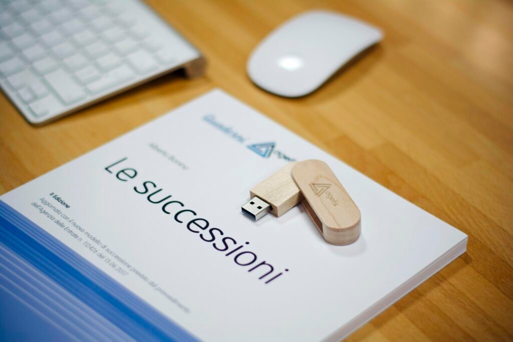 Brauner USB-Stick liegt neben einer Apple Magic Mouse und einer Apple Tastatur auf weißem Schreibtisch