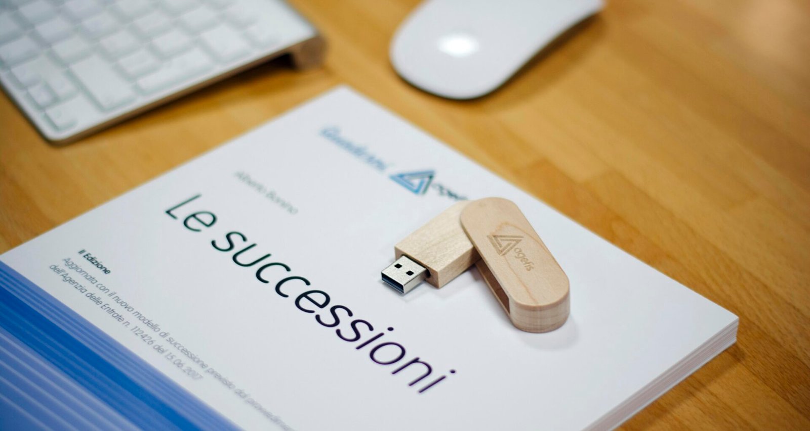 Brauner USB-Stick liegt neben einer Apple Magic Mouse und einer Apple Tastatur auf weißem Schreibtisch