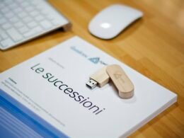 Brauner USB-Stick liegt neben einer Apple Magic Mouse und einer Apple Tastatur auf weißem Schreibtisch