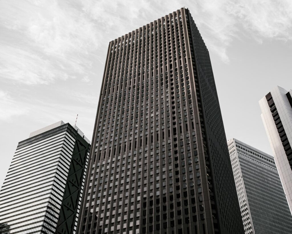 Braun-schwarzes Betongebäude unter weißen Wolken am Tag, mit moderner Fassadenstruktur in urbaner Umgebung
