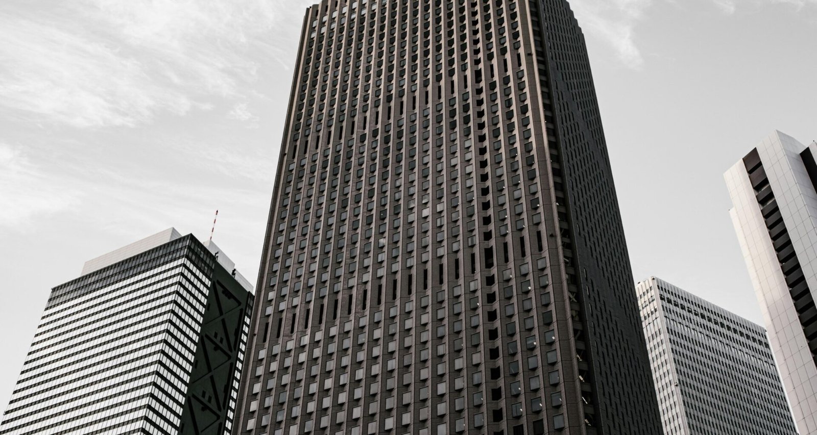 Braun-schwarzes Betongebäude unter weißen Wolken am Tag, mit moderner Fassadenstruktur in urbaner Umgebung