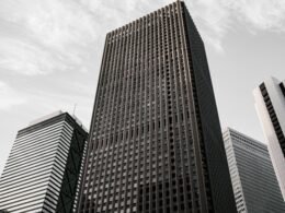 Braun-schwarzes Betongebäude unter weißen Wolken am Tag, mit moderner Fassadenstruktur in urbaner Umgebung