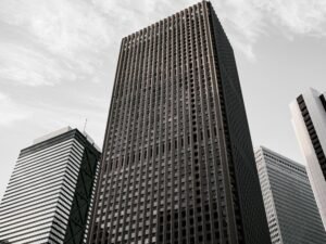 Braun-schwarzes Betongebäude unter weißen Wolken am Tag, mit moderner Fassadenstruktur in urbaner Umgebung