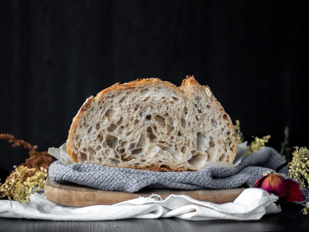 Ein Laib Brot auf einem weiß-blauen Stofftuch, rustikal angerichtet als Symbol für frische Backwaren und kulinarische Vielfalt.