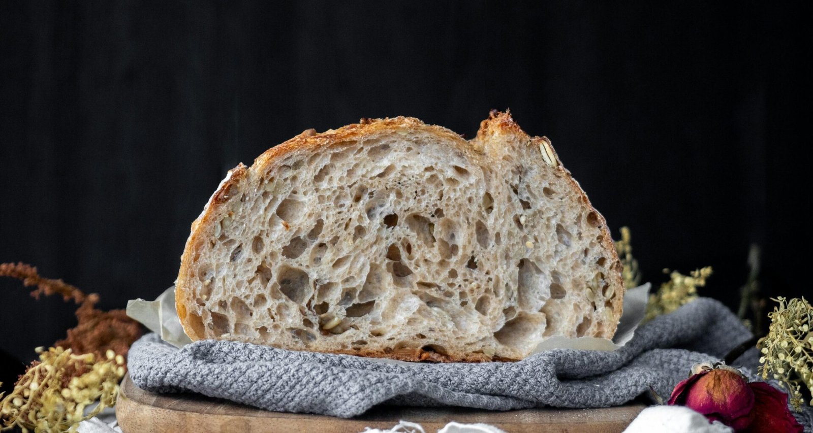 Ein Laib Brot auf einem weiß-blauen Stofftuch, rustikal angerichtet als Symbol für frische Backwaren und kulinarische Vielfalt.
