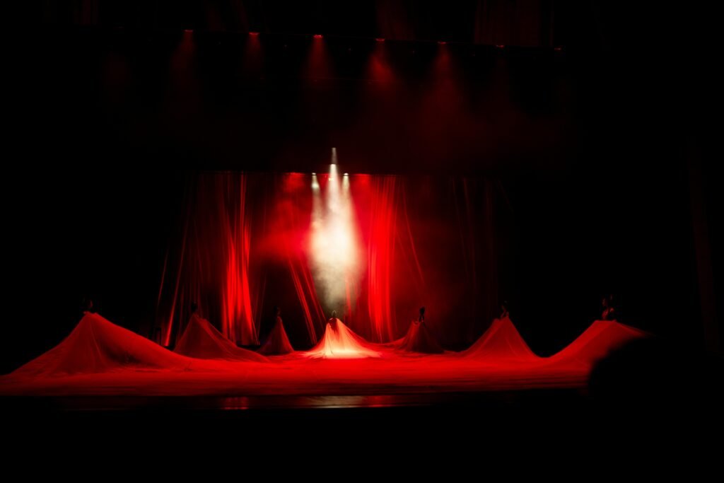 Eine Bühne mit roten Lichtern und sanftem Nebel, die eine dynamische Atmosphäre für Events oder Konzerte schafft.
