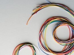 Bunte, spiralförmig gewickelte Kabel liegen auf einem grauen Untergrund, Detailaufnahme für Technikthemen.
