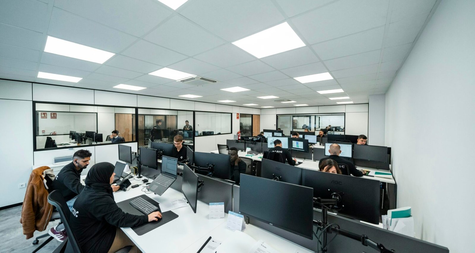 Mehrere Büroangestellte arbeiten konzentriert an ihren Computern in einem modernen Großraumbüro