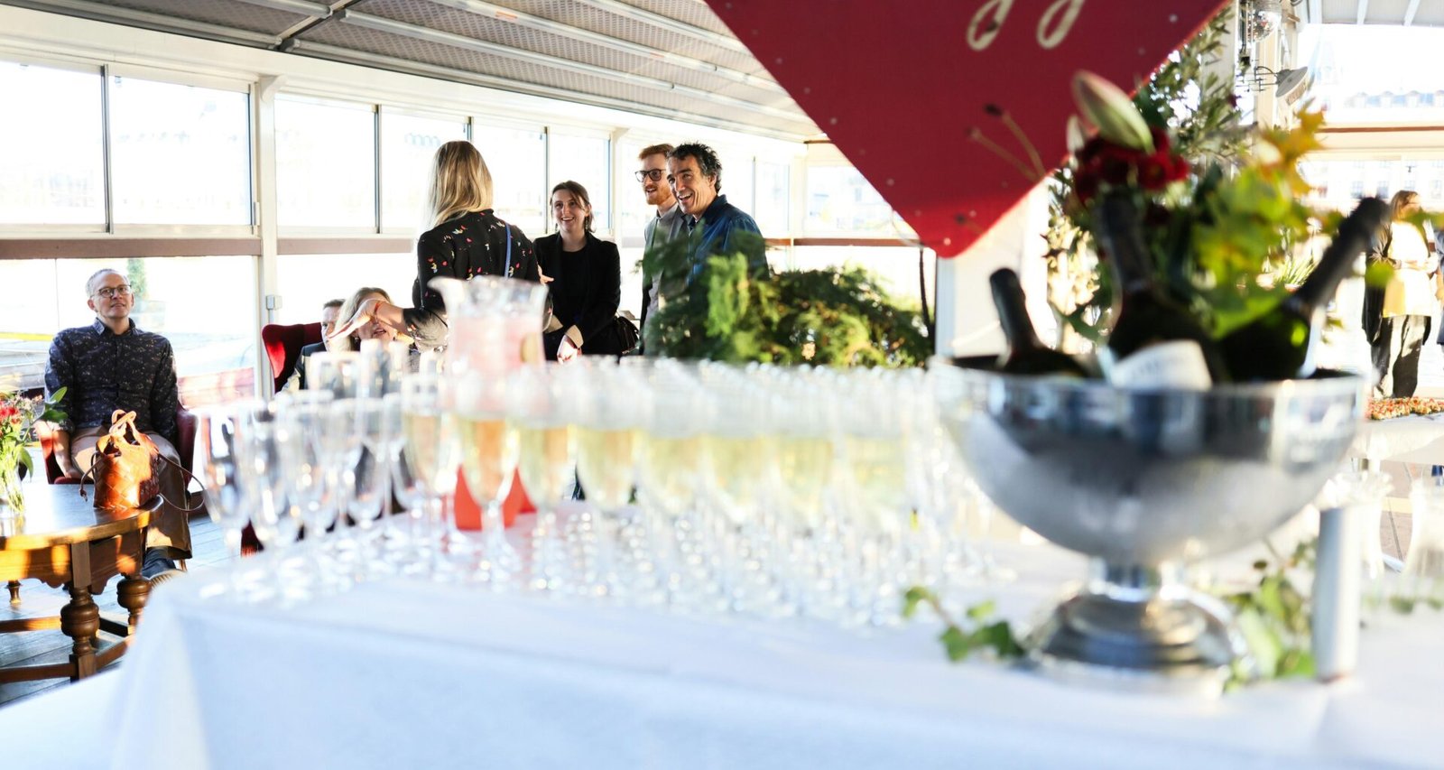 Mehrere Champagnergläser und Flaschen stehen auf einem Tisch und sorgen für festliche Atmosphäre bei einem Event.