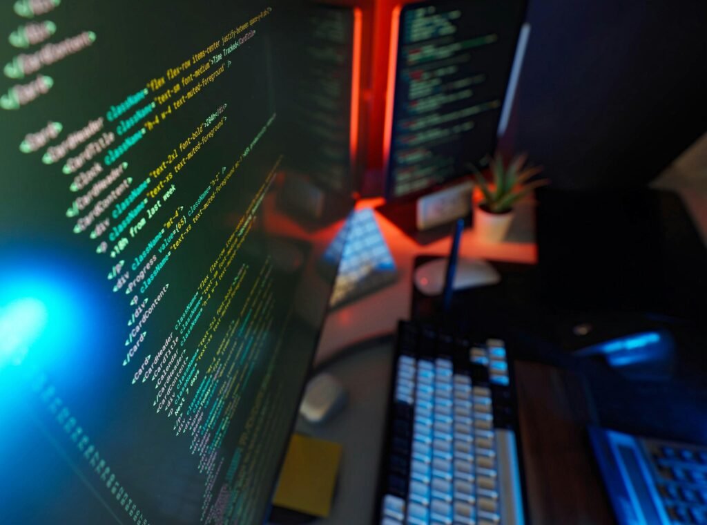 Programmierer arbeitet an einem Schreibtisch mit zwei Monitoren, auf denen Code angezeigt wird