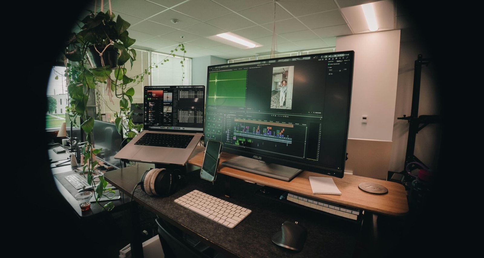 Moderne Computer-Workstation mit drei Monitoren, Tastatur und Zimmerpflanzen auf dem Schreibtisch