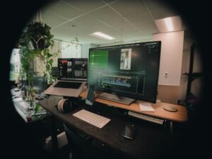 Computerarbeitsplatz mit mehreren Monitoren, Tastatur und grünen Pflanzen auf dem Schreibtisch, moderner Arbeitsbereich