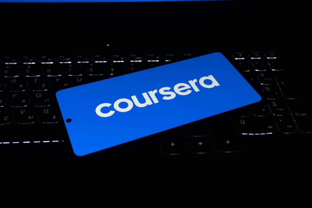 Das Coursera Logo erscheint auf dem Display eines Laptops, aufgenommen aus der Nähe mit Fokus auf die Tastatur.