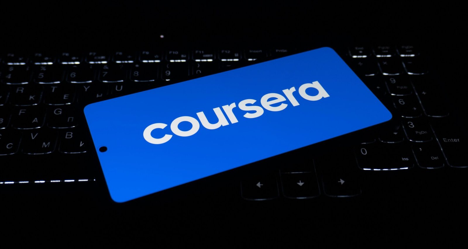 Das Coursera Logo erscheint auf dem Display eines Laptops, aufgenommen aus der Nähe mit Fokus auf die Tastatur.