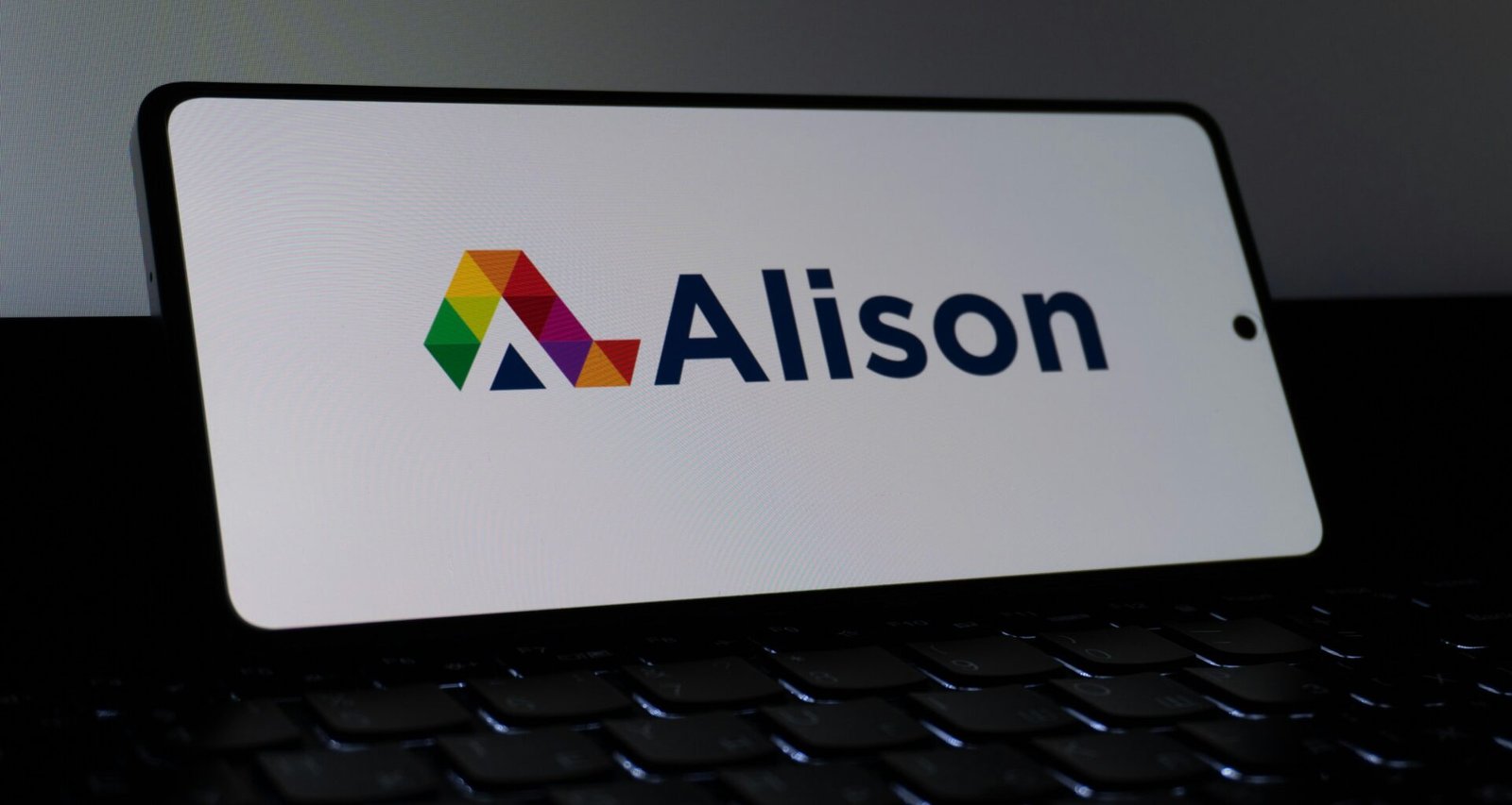 Das Alison Logo erscheint deutlich auf dem Bildschirm eines Smartphones vor neutralem Hintergrund.