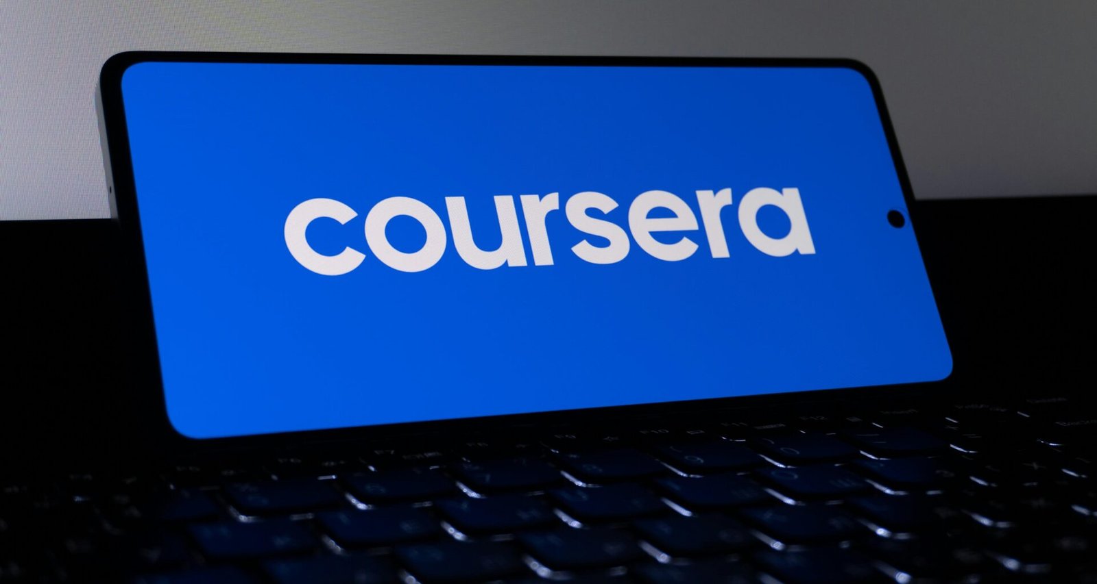 Das Coursera-Logo ist auf dem Bildschirm eines Smartphones deutlich sichtbar, fotografiert aus der Nähe.
