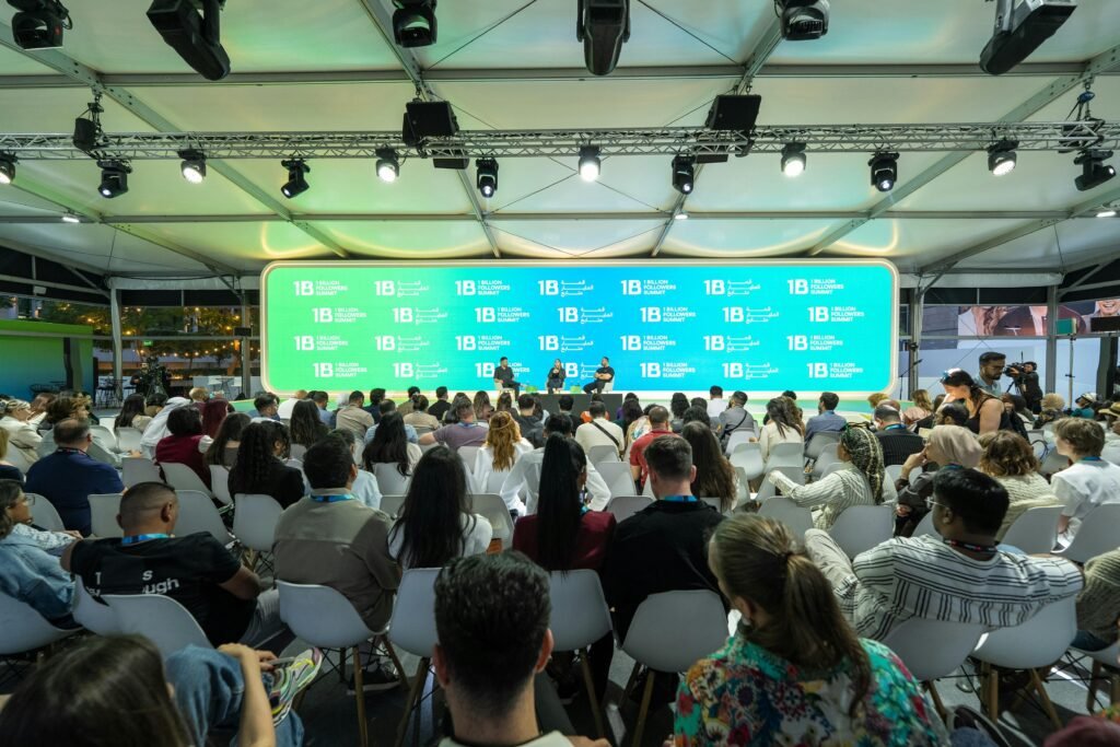Zuschauer betrachten eine Präsentation auf einer großen Leinwand im Konferenzraum mit moderner Technik.