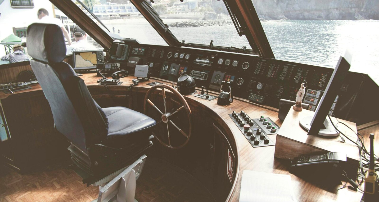 Detailansicht eines hölzernen Schiffssteuerrads, fotografiert aus der Nähe mit scharfem Fokus auf die Griffe