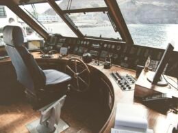 Detailansicht eines hölzernen Schiffssteuerrads, fotografiert aus der Nähe mit scharfem Fokus auf die Griffe