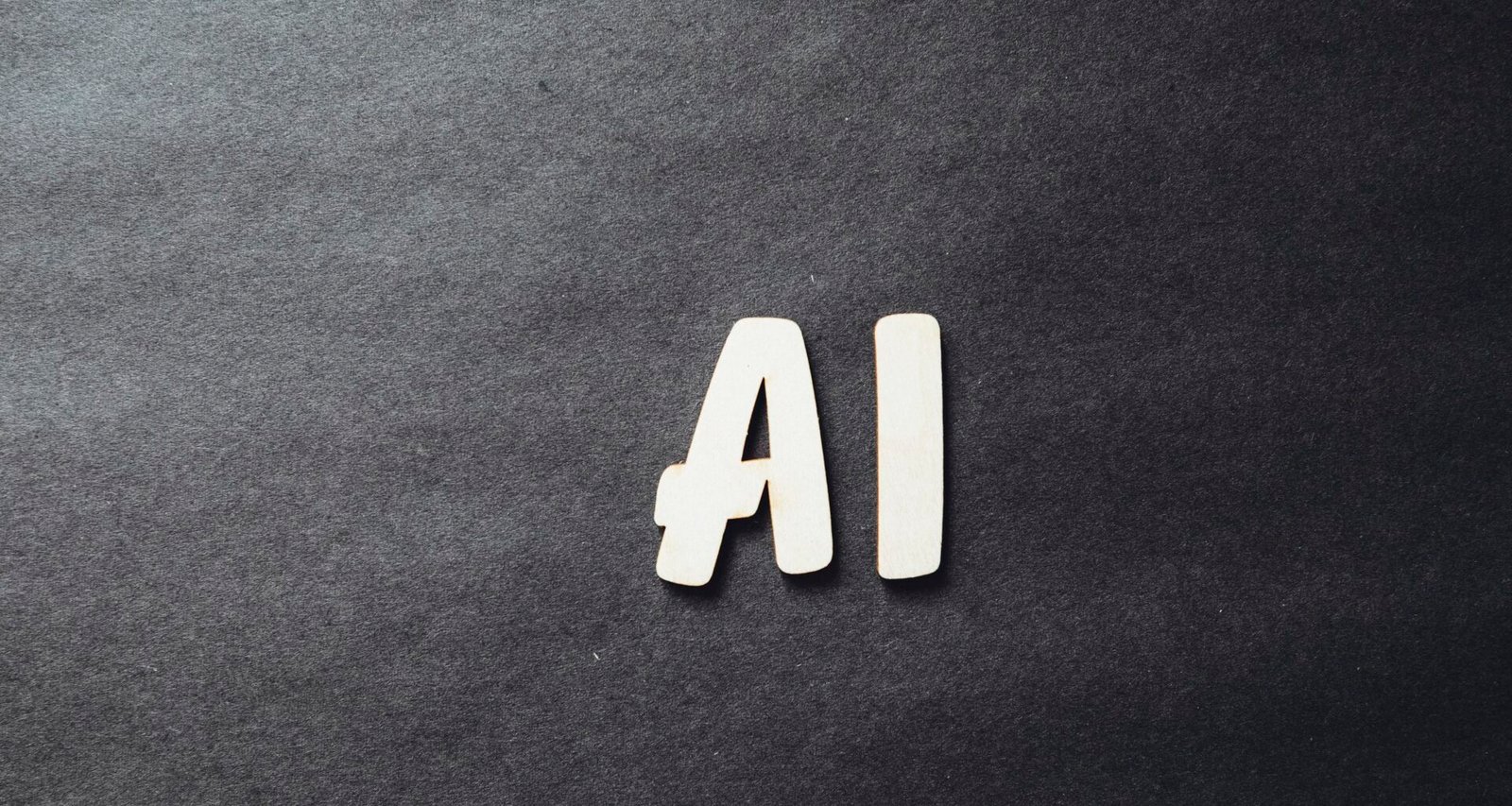 Das Wort AI ist in weißen Buchstaben deutlich auf einer schwarzen Oberfläche dargestellt, als Zeichen für künstliche Intelligenz.