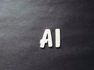 Weiße Buchstaben formen das Wort 'AI' auf einer schwarzen Oberfläche als Symbol für künstliche Intelligenz.