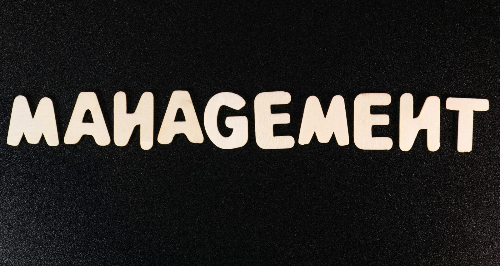 Weißes Wort Management auf schwarzem Hintergrund, neutral gehalten und passend zum Thema Führung und Organisation dargestellt