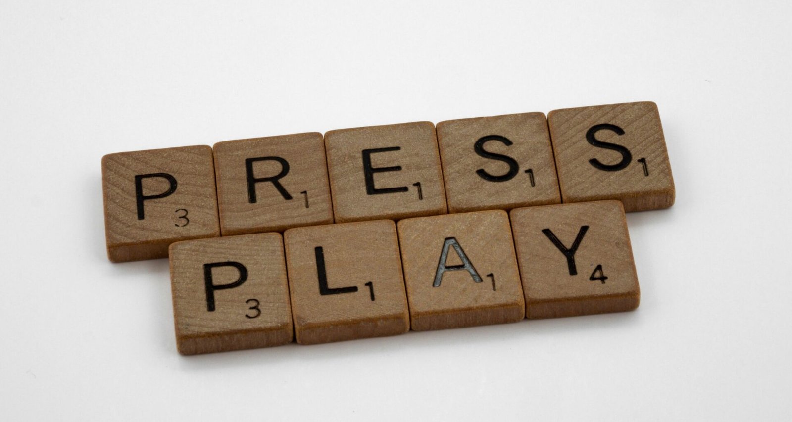 Scrabble-Buchstaben liegen dicht beieinander und buchstabieren das Wort 'Play' auf einer ebenen Fläche.