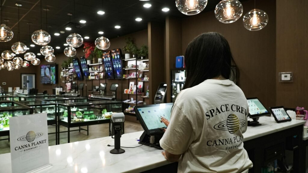 Kunde interagiert am Verkaufstresen eines Dispensary mit einem Tablet und erhält Beratung durch das Personal.