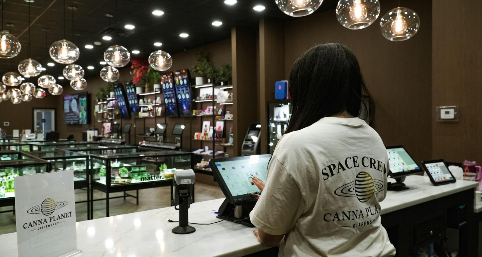 Kunde verwendet ein Tablet am Tresen eines Dispensary-Shops zur digitalen Bestellung und Beratung.