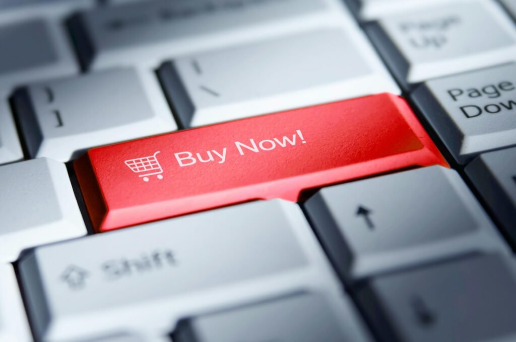 Nahaufnahme eines roten 'Buy Now!' Buttons auf einer Computertastatur als Symbol für Online-Shopping und digitale Kaufvorgänge.
