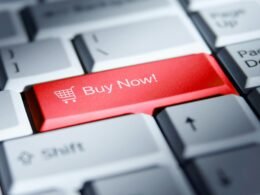 Roter 'Buy Now!' Button auf einer weißen Computertastatur als Symbol für Online-Shopping und E-Commerce
