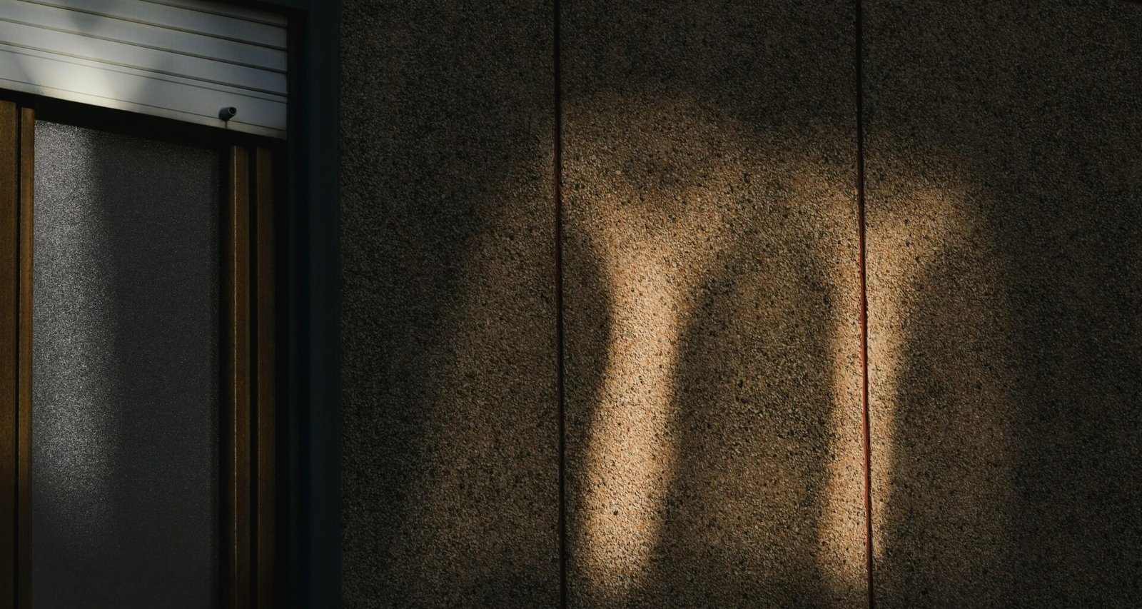 Schatten eines menschlichen Beins streckt sich deutlich auf einer hellen Wand, aufgenommen mit natürlichem Licht
