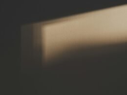 Der Schatten eines rechteckigen Fensters fällt klar erkennbar auf eine helle Wand in einem Innenraum.