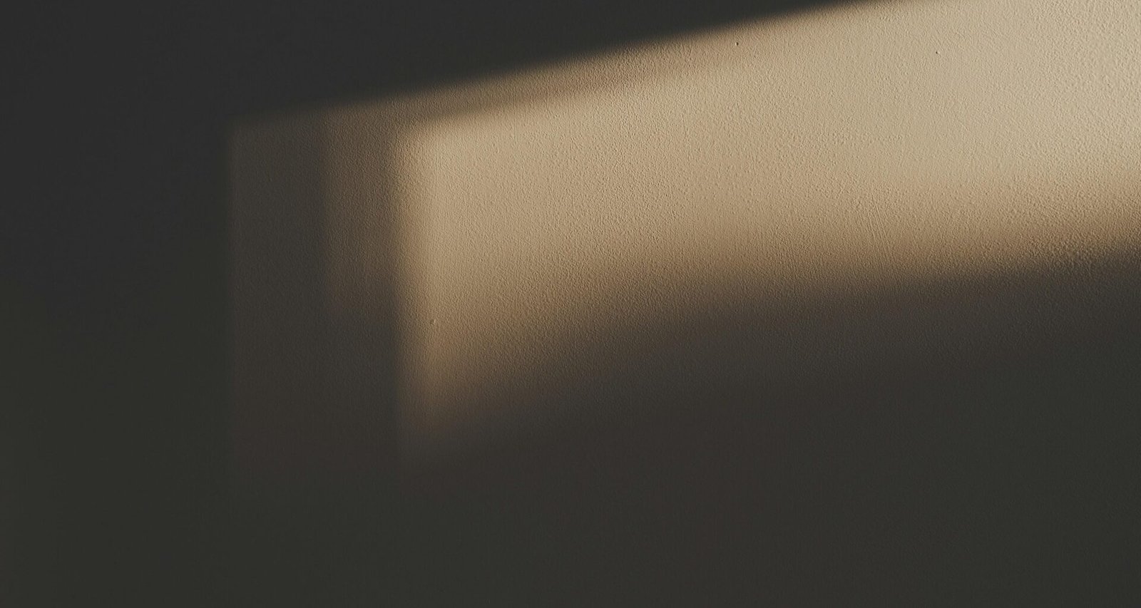 Der Schatten eines rechteckigen Fensters fällt auf eine helle Wand und erzeugt geometrische Muster im Innenraum.