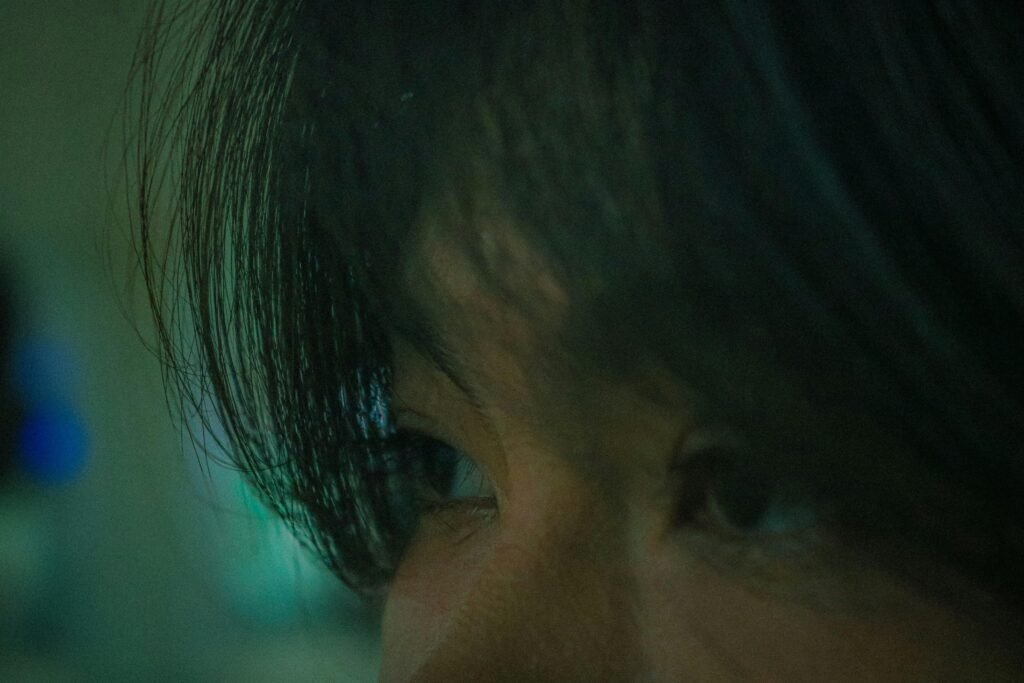 Nahaufnahme von Augen, die bei gedämpfter Beleuchtung intensiv auf etwas fokussiert sind, ideal für Themen zu Konzentration oder Analyse