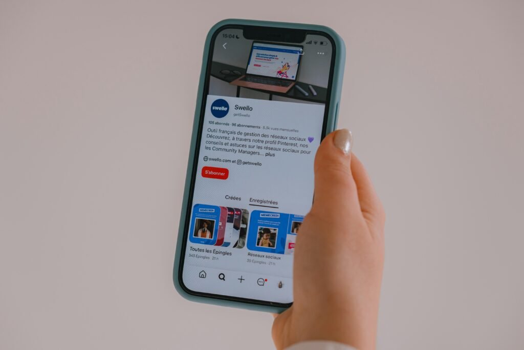 Hand hält ein Smartphone, auf dessen Bildschirm ein Social Media Feed dargestellt wird, Fokus auf moderner digitaler Kommunikation