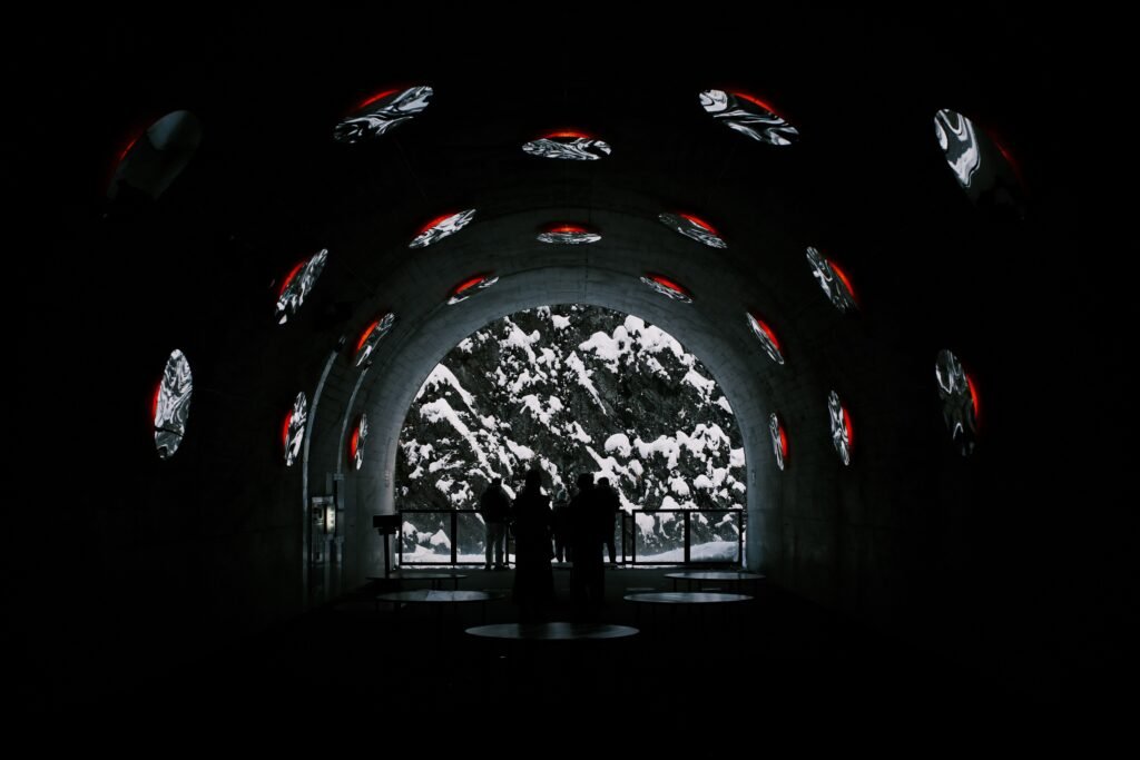 Mehrere Personen gehen durch einen Tunnel mit Wänden, auf die digitale Bilder und visuelle Projektionen geworfen werden.