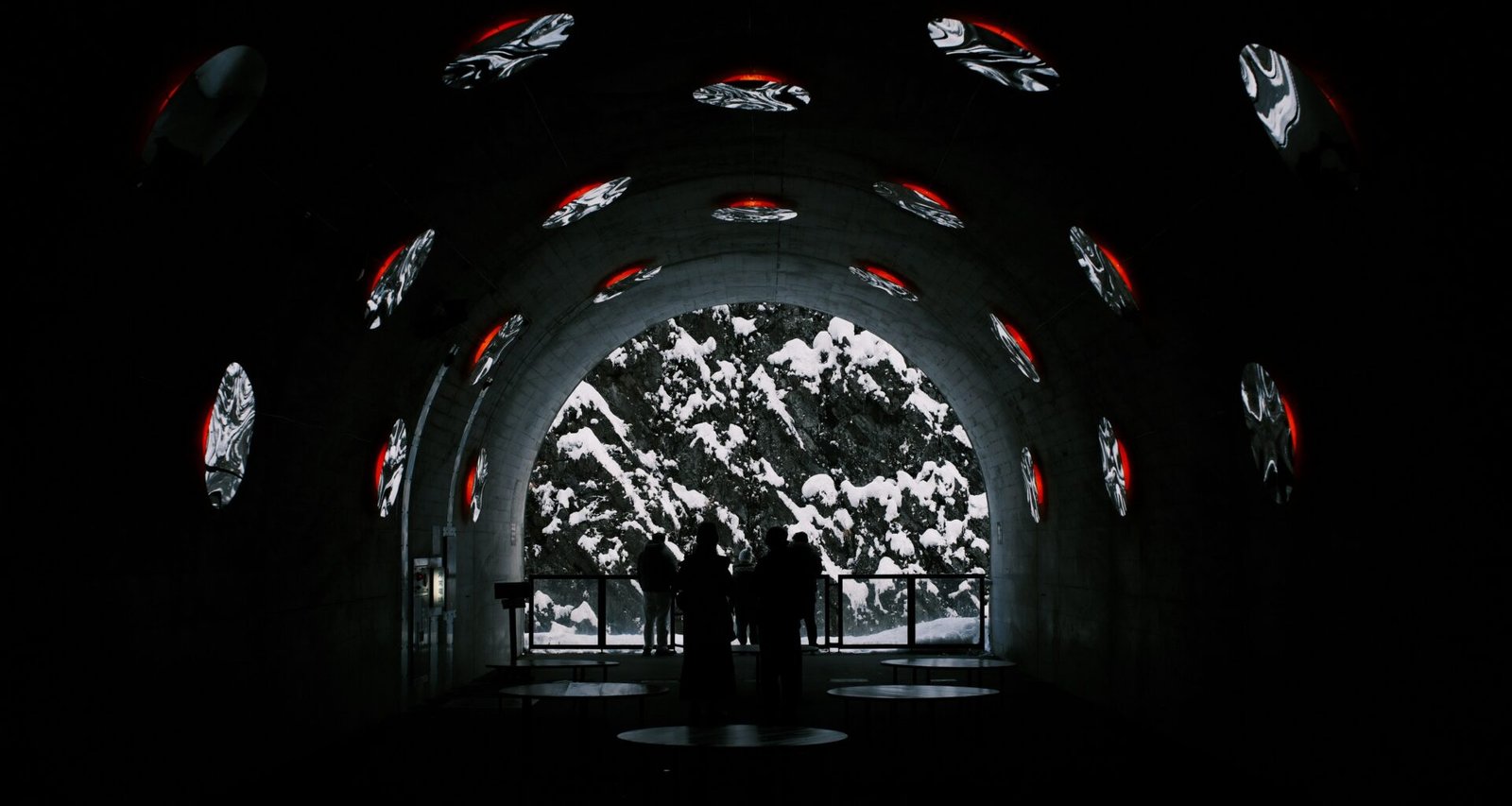 Mehrere Personen gehen durch einen Tunnel mit Wänden, auf die digitale Bilder und visuelle Projektionen geworfen werden.