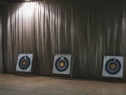 Drei bunte Bogenschieß-Zielscheiben nebeneinander aufgestellt vor einem neutralen Vorhang