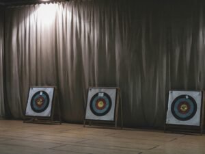 Drei bunte Bogenschieß-Zielscheiben nebeneinander aufgestellt vor einem neutralen Vorhang