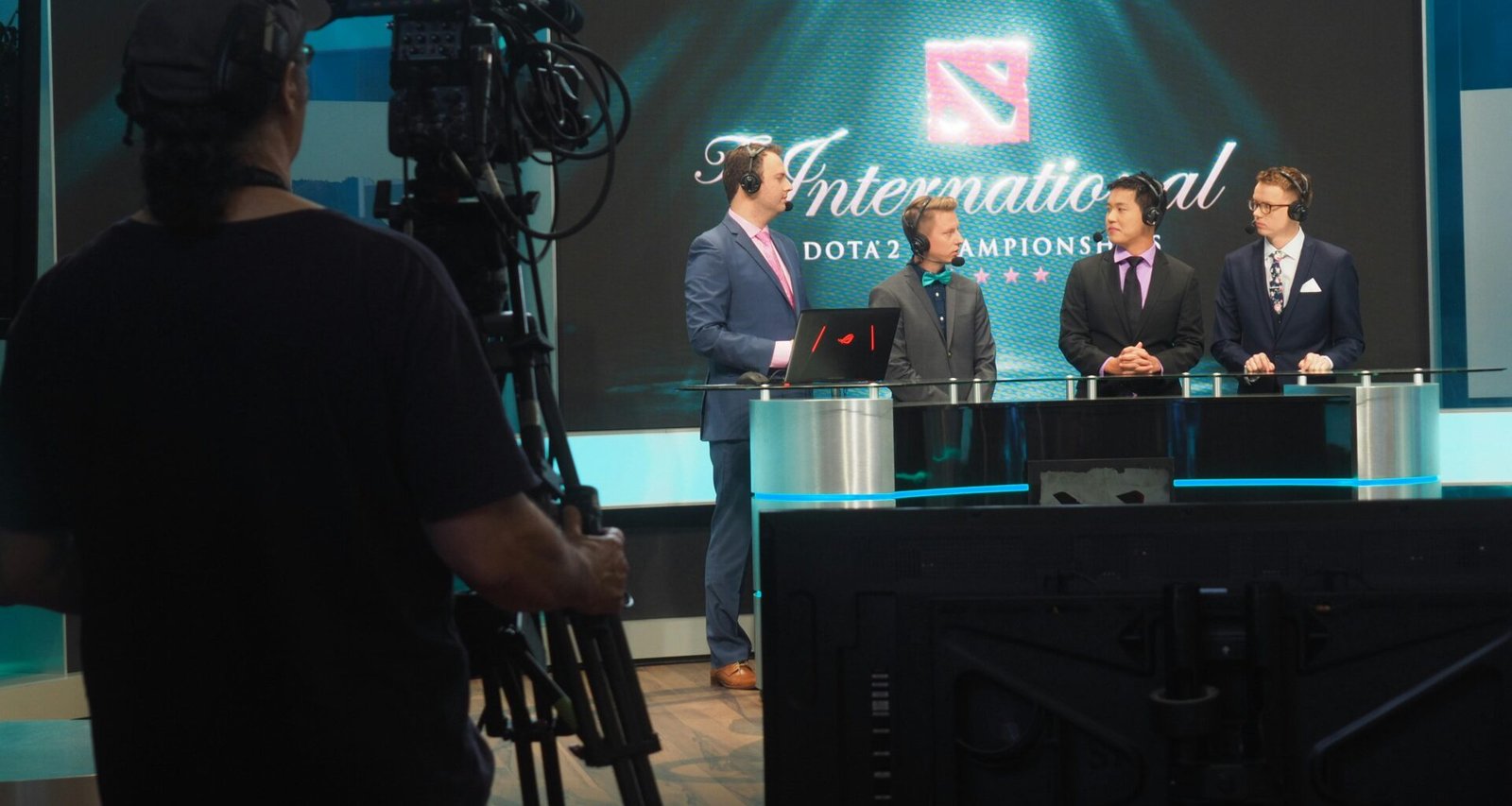 Drei Männer in Anzügen werden bei einem Dota 2 E-Sport-Event für eine Übertragung gefilmt