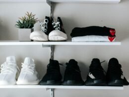 Drei Paar schwarze und weiße Schuhe auf einem schwebenden Regal, minimalistisch angeordnet vor einer neutralen Wand